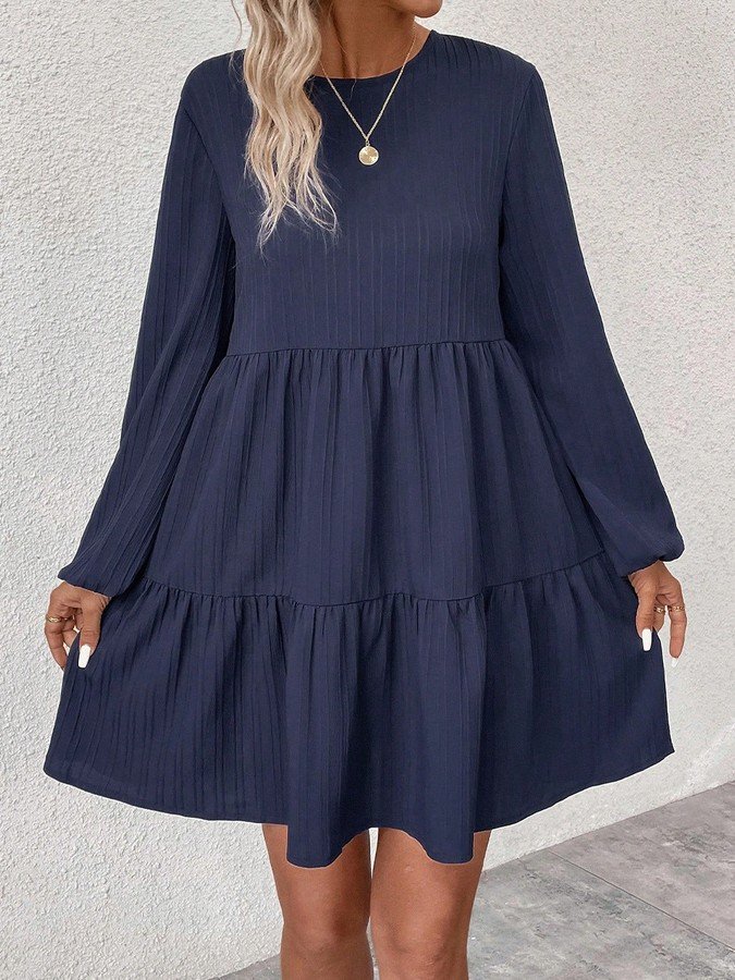Angled front view of the navy long-sleeve tiered smock dress, showing its silhouette and design details.