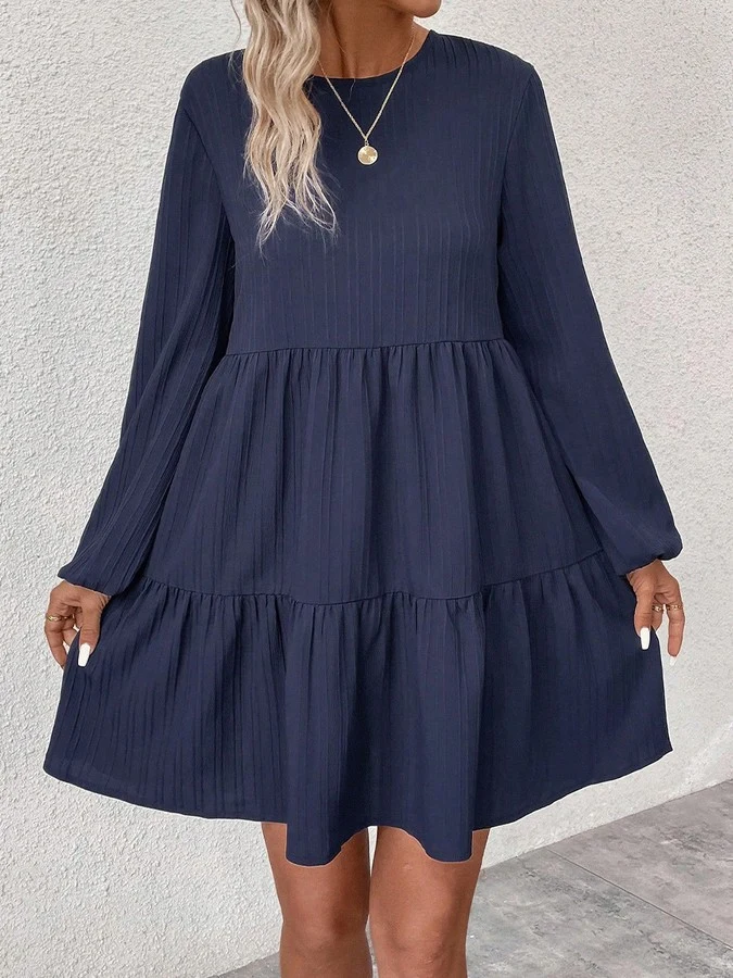 Angled front view of the navy long-sleeve tiered smock dress, showing its silhouette and design details.