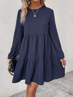 Three-quarter front view of the navy long-sleeve tiered smock dress, showing its silhouette and design details.