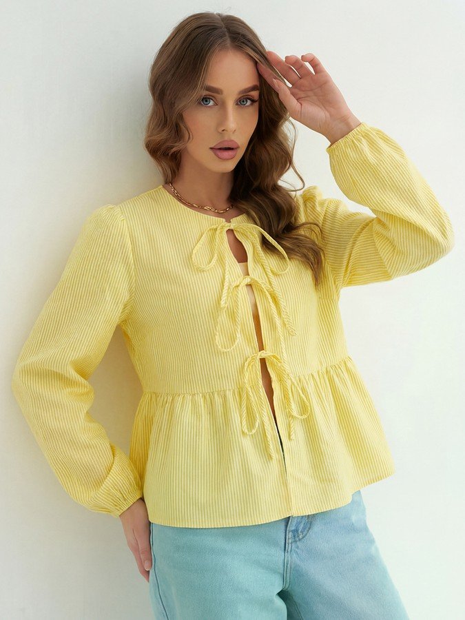 Angled front view of the yellow tie-front long-sleeve blouse, showing its silhouette and design details.