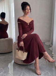 Seated front view of the burgundy off-shoulder pleated a-line midi dress, showing the silhouette and fit.