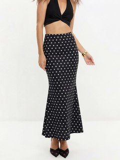 Angled front view of the black polka-dot fishtail maxi skirt, showing its silhouette and design details.