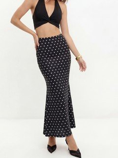 Three-quarter front view of the black polka-dot fishtail maxi skirt, showing its silhouette and design details.