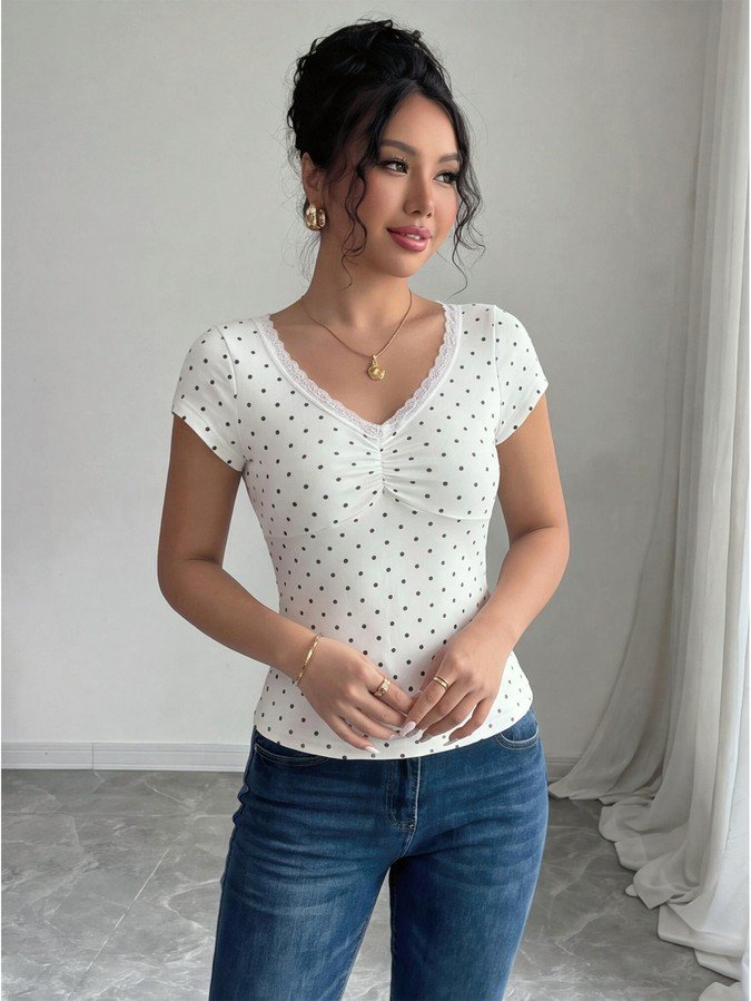 Angled front view of the white polka-dot lace-trim v-neck short-sleeve top, showing the silhouette and fit.