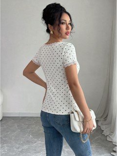 Side view of the white polka-dot lace-trim v-neck short-sleeve top, showing the silhouette and fit.