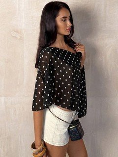 Full-length front view of the black polka-dot asymmetric drape blouse, showing its silhouette and design details.
