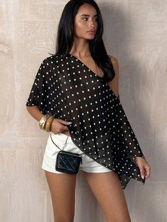 Styled front view of the black polka-dot asymmetric drape blouse, showing its silhouette and design details.