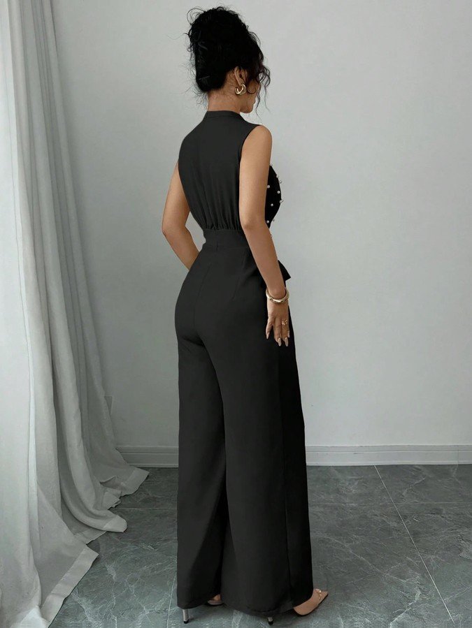 Back view of the black polka-dot sleeveless tie-waist wide-leg jumpsuit, showing the silhouette and fit.