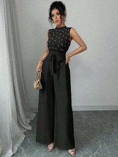 Angled front view of the black polka-dot sleeveless tie-waist wide-leg jumpsuit, showing the silhouette and fit.