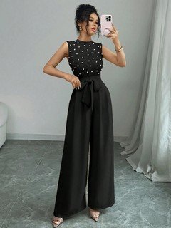 Full length front view of the black polka-dot sleeveless tie-waist wide-leg jumpsuit, showing the silhouette and fit.