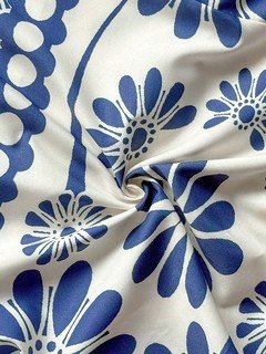Fabric detail of the blue porcelain floral smocked-bodice spaghetti-strap maxi dress, showing smocked bodice, slim straps and porcelain floral print.
