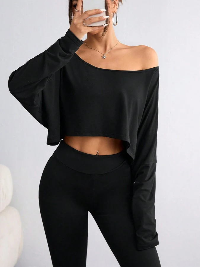 Angled front view of the black off-shoulder high-low crop top, showing its silhouette and design details.