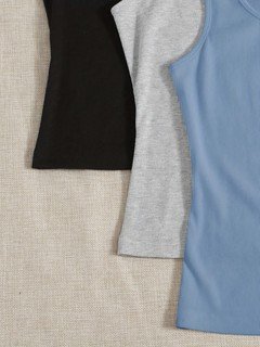 Side detail of the assorted colors ribbed sleeveless cropped tank top collection, showing assorted necklines, rib texture and cropped fit.