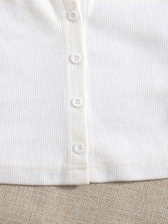 Button detail of the white ribbed square-neck button-front cropped tank top, showing square neckline, ribbed texture and button front.