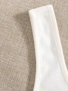Ribbed fabric detail of the white ribbed square-neck button-front cropped tank top, showing square neckline, ribbed texture and button front.