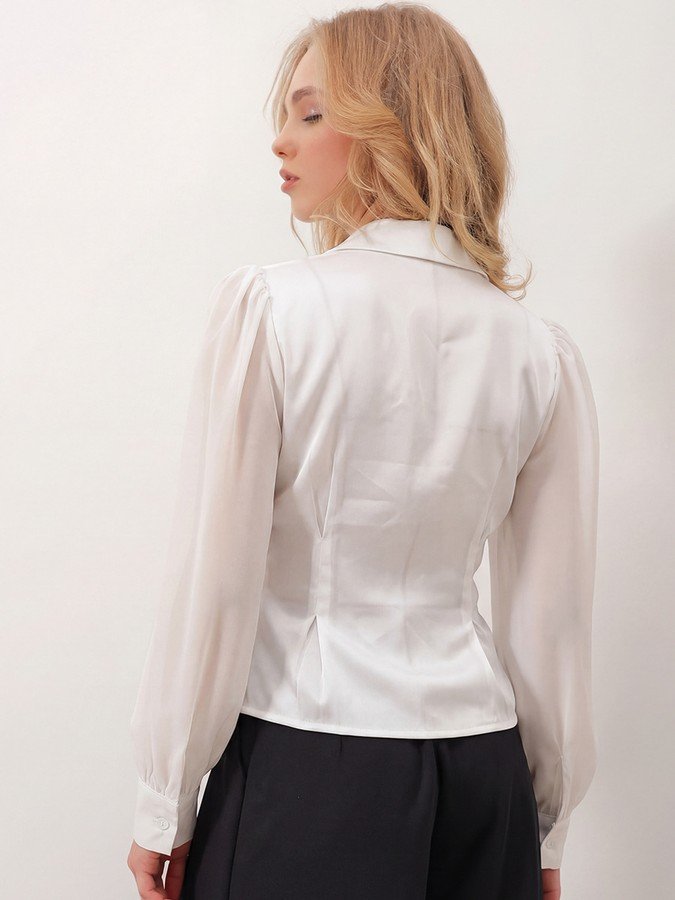 Back view of the ivory satin button-detail wrap blouse, showing its silhouette and design details.