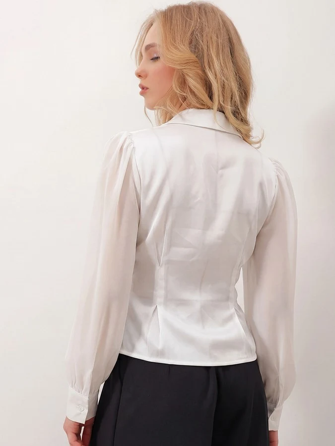 Back view of the ivory satin button-detail wrap blouse, showing its silhouette and design details.