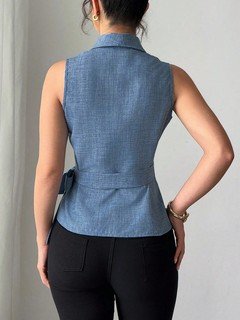 Back view of the blue sleeveless side-tie wrap top, showing its silhouette and design details.