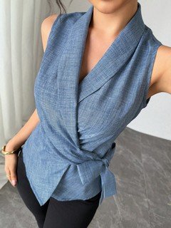 Close-up of the blue sleeveless side-tie wrap top, showing its silhouette and design details.