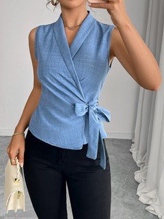 Studio front view of the blue sleeveless side-tie wrap top, showing its silhouette and design details.