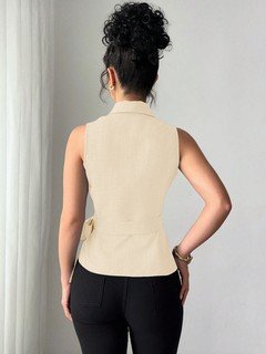 Back view of the cream sleeveless side-tie wrap top, showing its silhouette and design details.