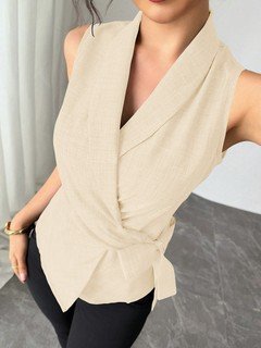 Close-up of the cream sleeveless side-tie wrap top, showing its silhouette and design details.