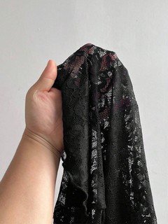 Fabric detail of the black floral lace mock-neck top, showing the surface texture and finish.