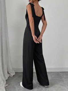 Side view of the black square-neck tie-strap wide-leg jumpsuit, showing the silhouette and fit.