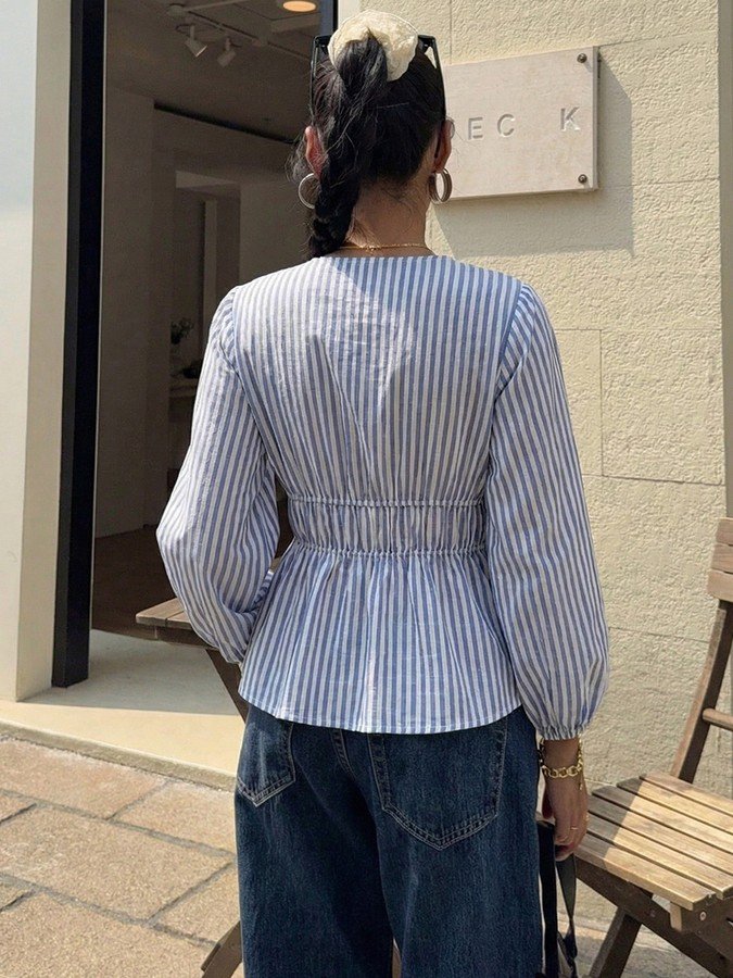 Back view of the blue and white striped tie-front peplum blouse, showing its silhouette and design details.