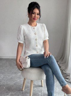 Seated front view of the white textured button-front short-sleeve blouse, showing the silhouette and fit.