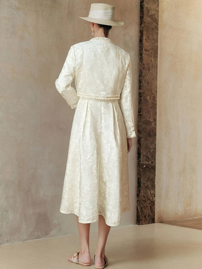 Back view of the cream textured jacket and dress set, showing its silhouette and design details.