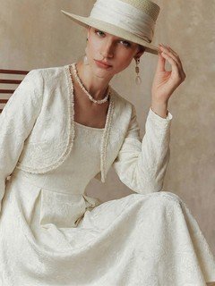 Angled front view of the cream textured jacket and dress set, showing its silhouette and design details.