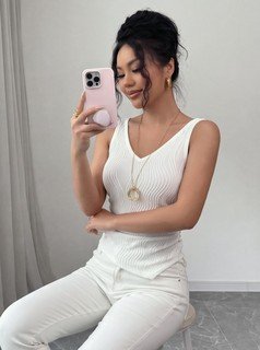Seated front view of the white textured v-neck ruched sleeveless tank top, showing the silhouette and fit.