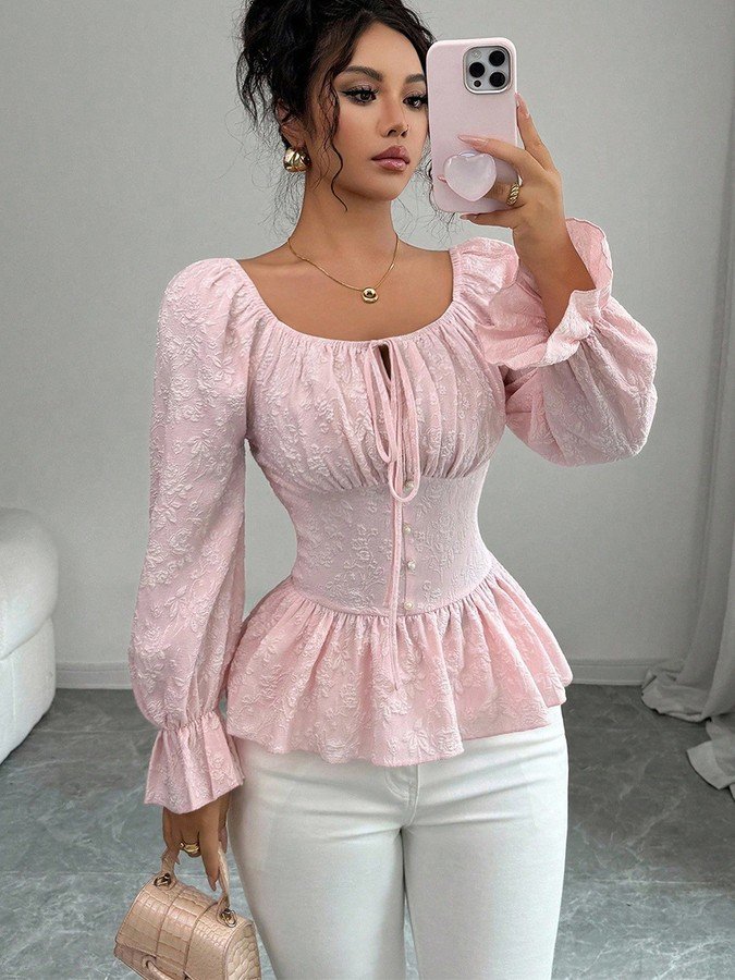 Angled front view of the pink tie-neck corset peplum blouse, showing its silhouette and design details.