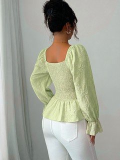 Back view of the light green tie-neck corset peplum blouse, showing its silhouette and design details.