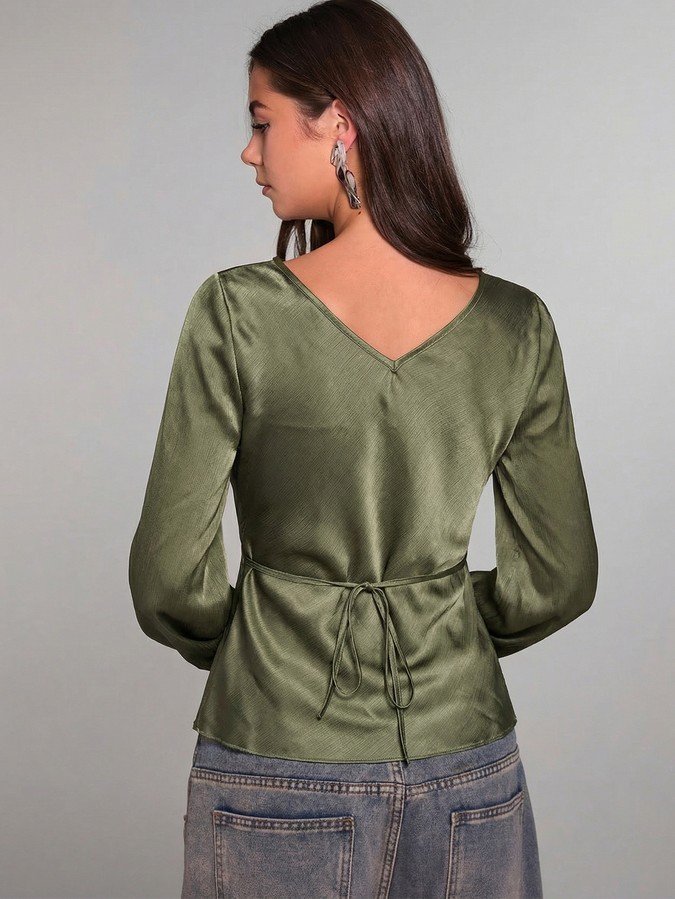 Back view of the olive green ruched tie-front bell-sleeve top, showing its silhouette and design details.