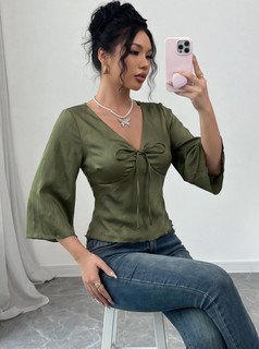 Seated front view of the olive v-neck bell-sleeve tie-waist blouse, showing the silhouette and fit.