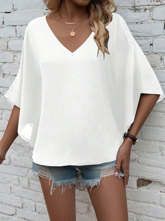 Angled front view of the white v-neck dolman-sleeve blouse, showing its silhouette and design details.