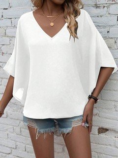 Angled front view of the white v-neck dolman-sleeve blouse, showing its silhouette and design details.