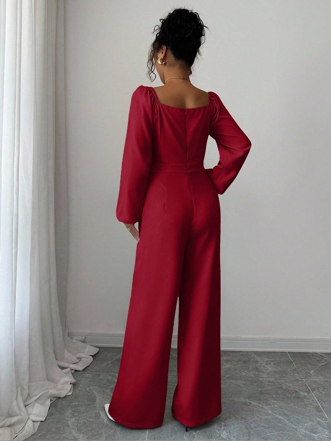 Back view of the red v-neck tie-waist long-sleeve wide-leg jumpsuit, showing the silhouette and fit.