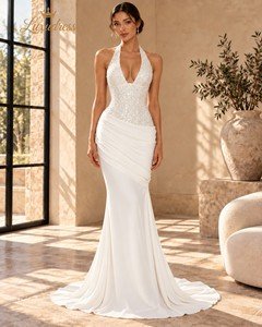 Front view of an ivory beaded mermaid prom dress with a deep halter neckline, draped hips and a flowing train.