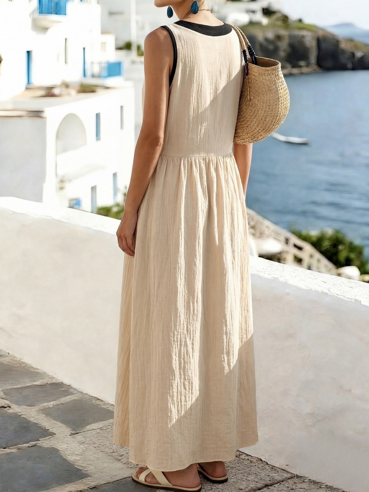 Back view of a beige cotton maxi dress with black trim and a front bow tie.