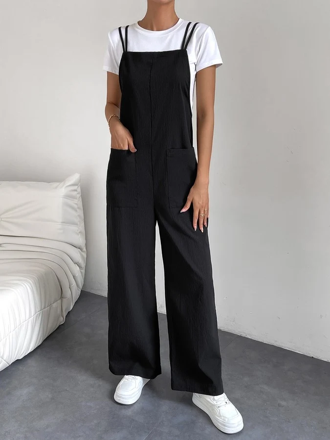Pocket front view of a black cotton wide-leg bib overall jumpsuit with patch pockets.