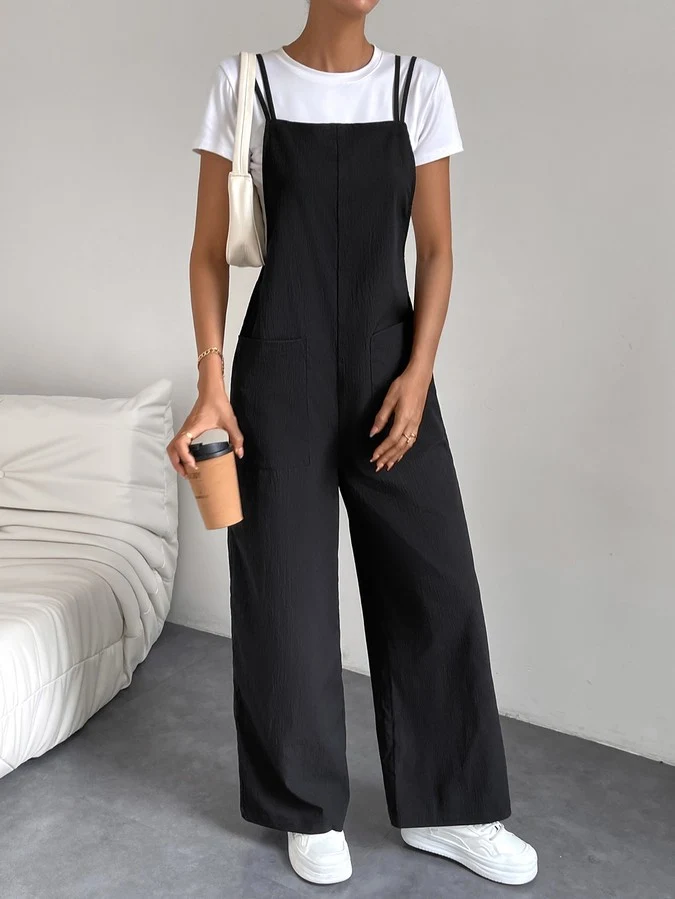 Primary front view of a black cotton wide-leg bib overall jumpsuit with patch pockets.