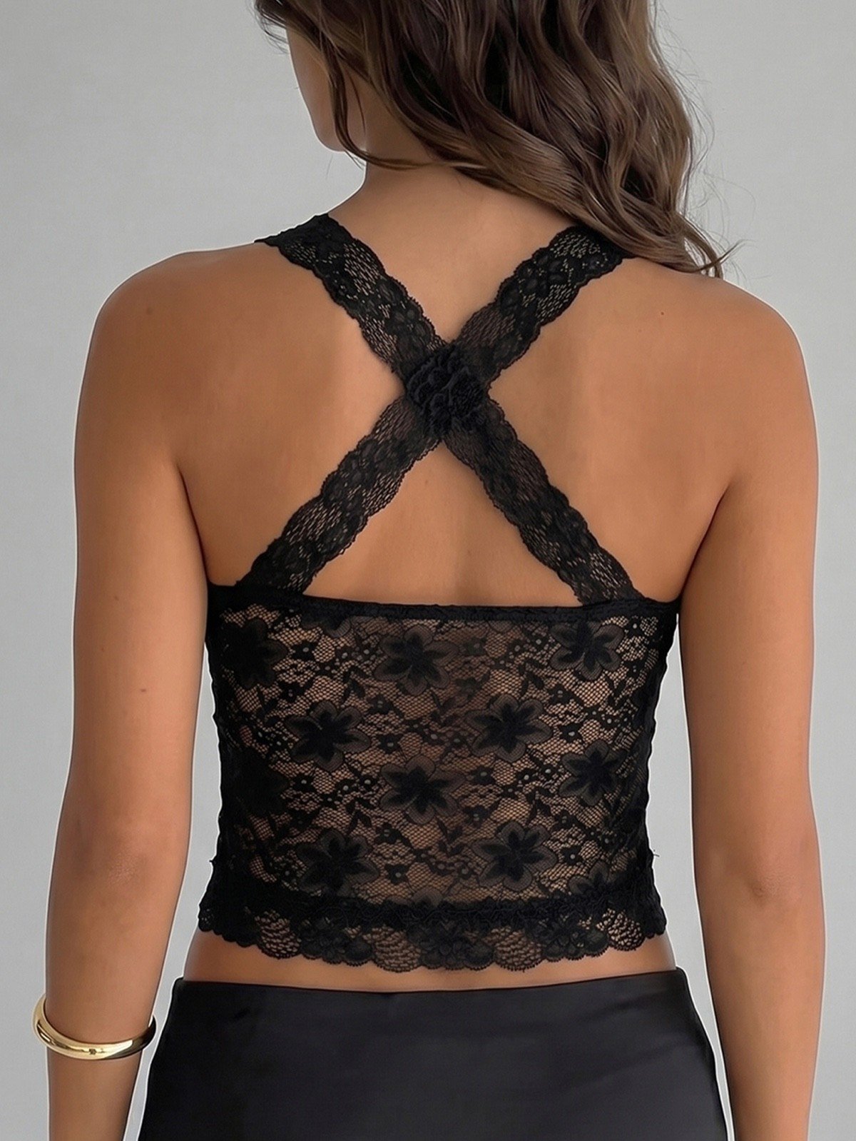 Cross-back close-up of a black floral lace halter corset crop top with cross-back straps.
