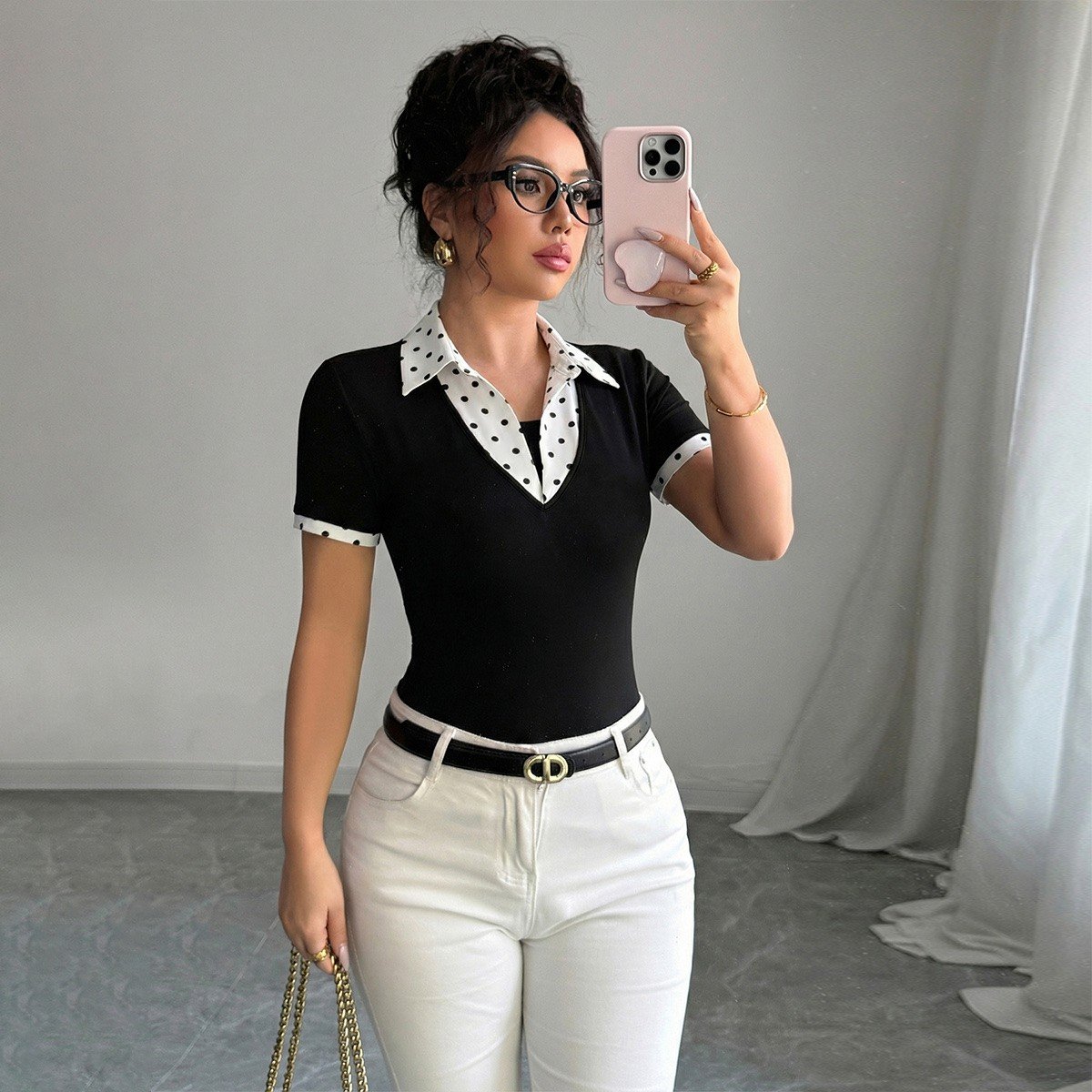 Square lifestyle view of a black fitted polo top with a white polka-dot collar and cuffs.