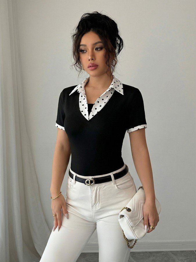 Front view of a black fitted polo top with a white polka-dot collar and cuffs.