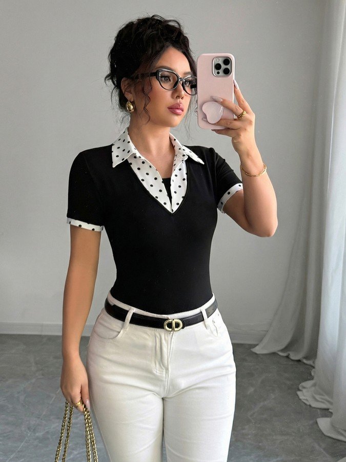 Mirror front view of a black fitted polo top with a white polka-dot collar and cuffs.