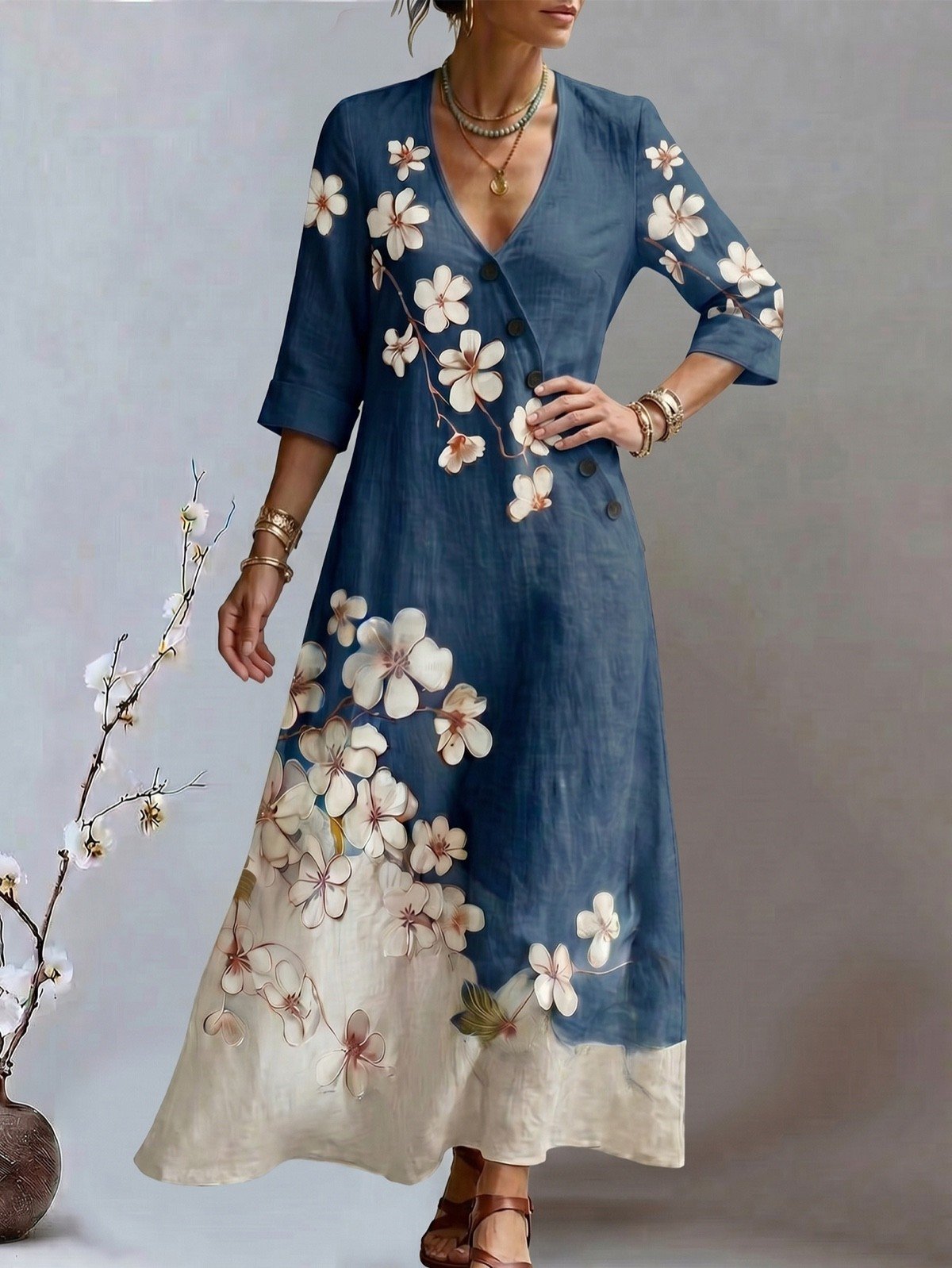 Hand-on-hip front view of a blue floral print V-neck maxi dress with three-quarter sleeves.