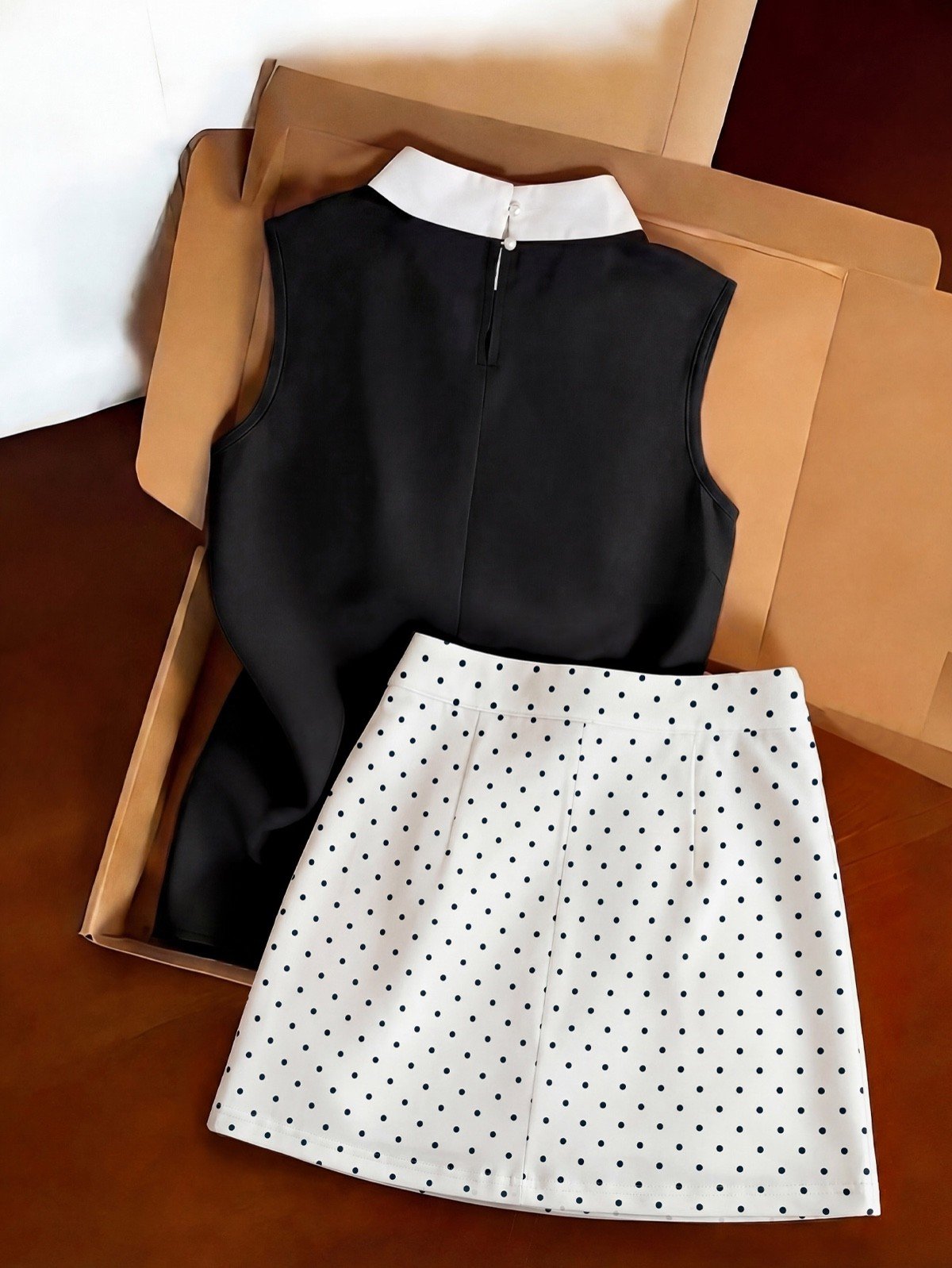 Back set flat-lay of a black bow-collar blouse and white polka-dot mini skirt set.